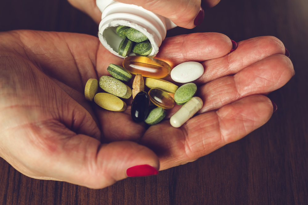 Assorted dietary supplement pills in a person's palm