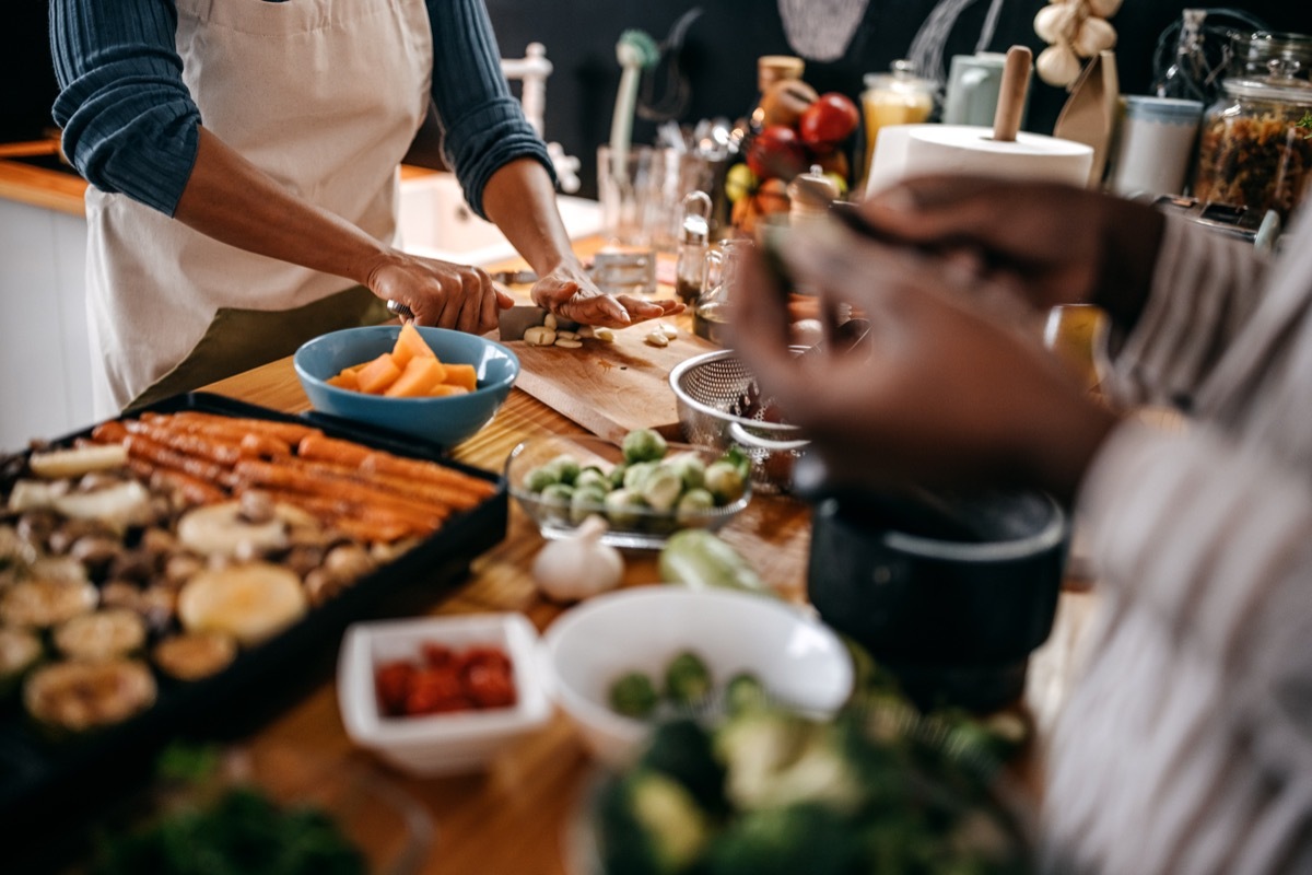 Two female friends preparing food in domestic kitchen for thanksgiving celebration