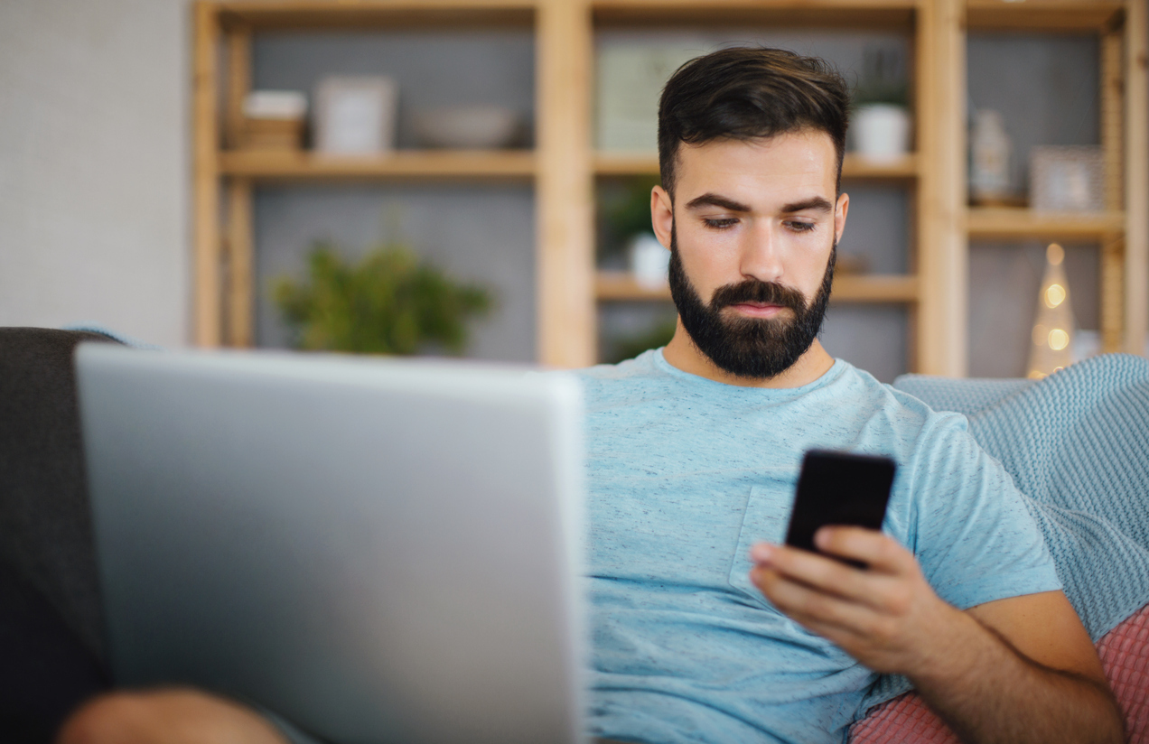 A man using a phone and his laptop