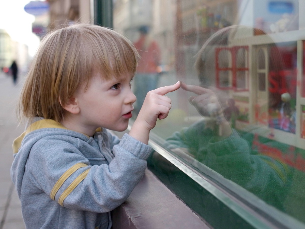 young white boy looking in the window of a toy store