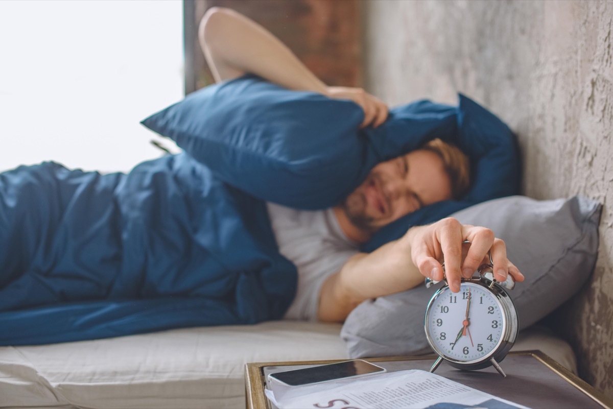 Angry man in bed hating Daylight Saving Time