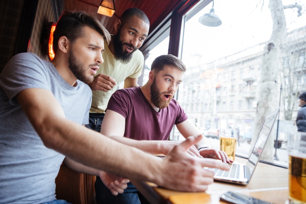 three guys look at a laptop