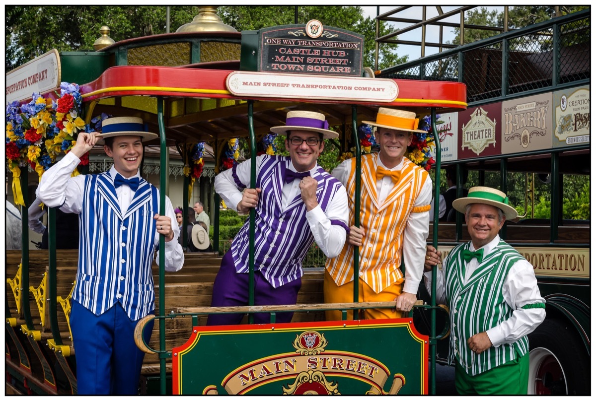 four men in retro dresses on a trolley during a dapper day in disneyland