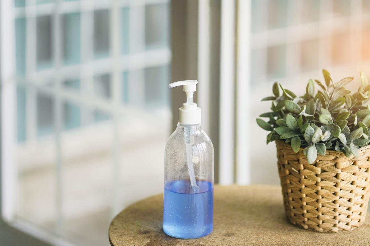 bottle of blue alcohol gel on table near door prepared for incoming guest , preventing corona virus