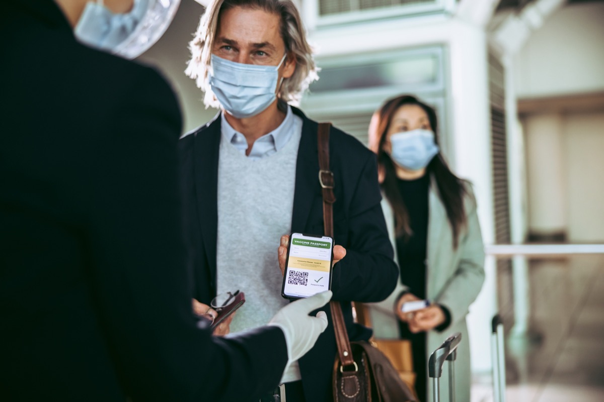 Passenger showing his vaccination passport to ground attendant