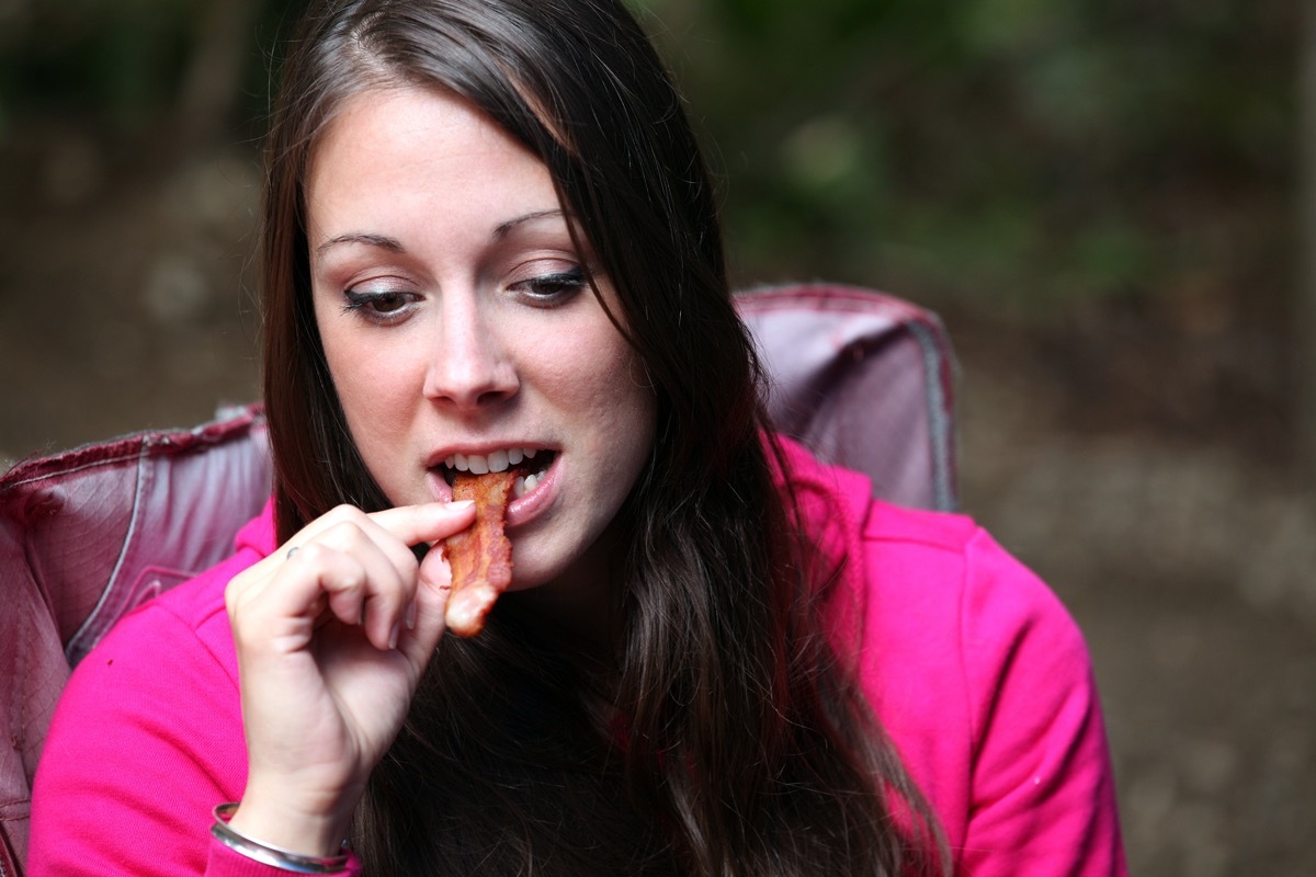 Woman enjoying a slice of bacon.