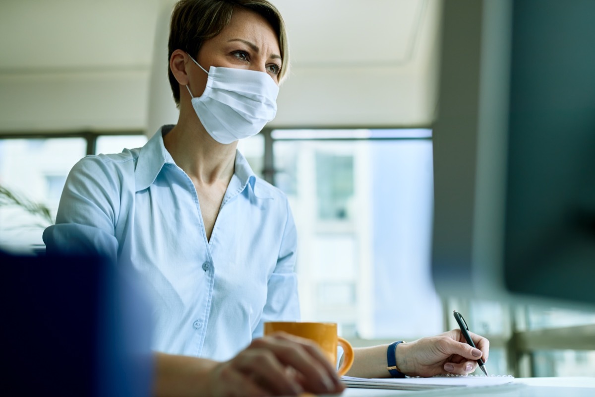 white woman using a computer with a mask on