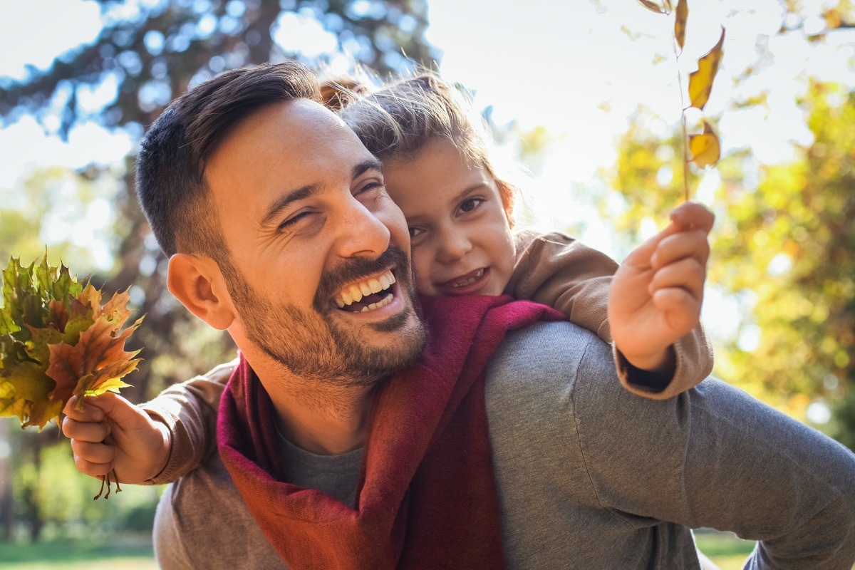 Father and daughter outside playing in leaves