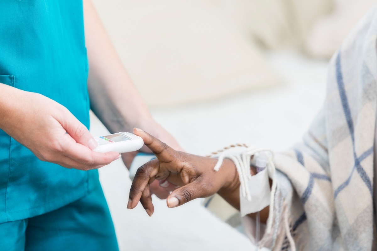 Unrecognizable woman uses a glaucometer to check a female patient's blood sugar level.