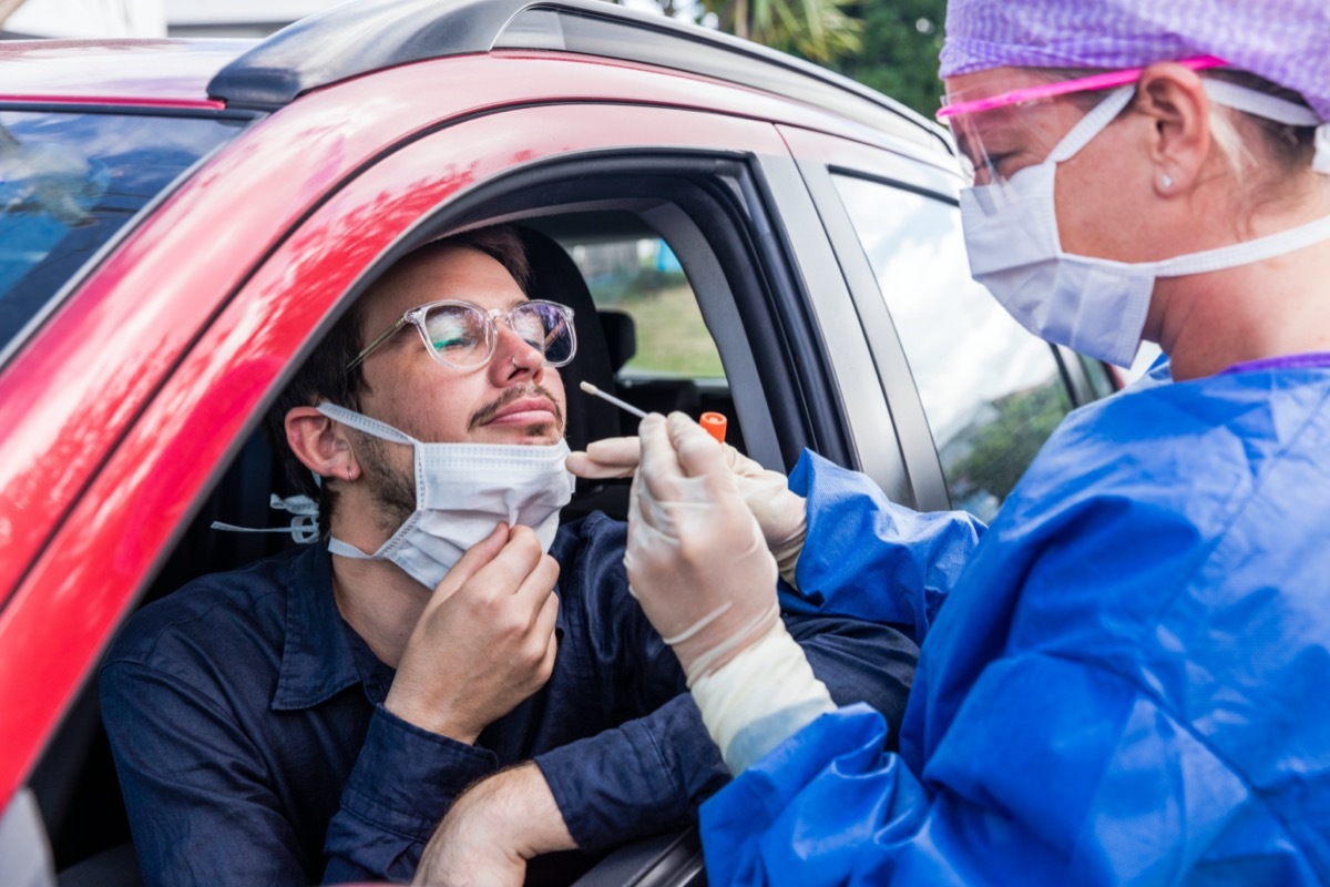 A doctor in a protective suit taking a nasal swab from a person to test for possible coronavirus infection