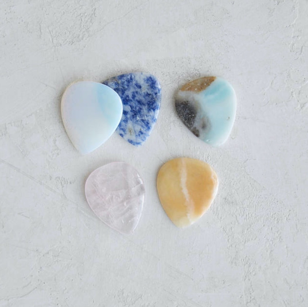 guitar picks made out of birthstones on white background