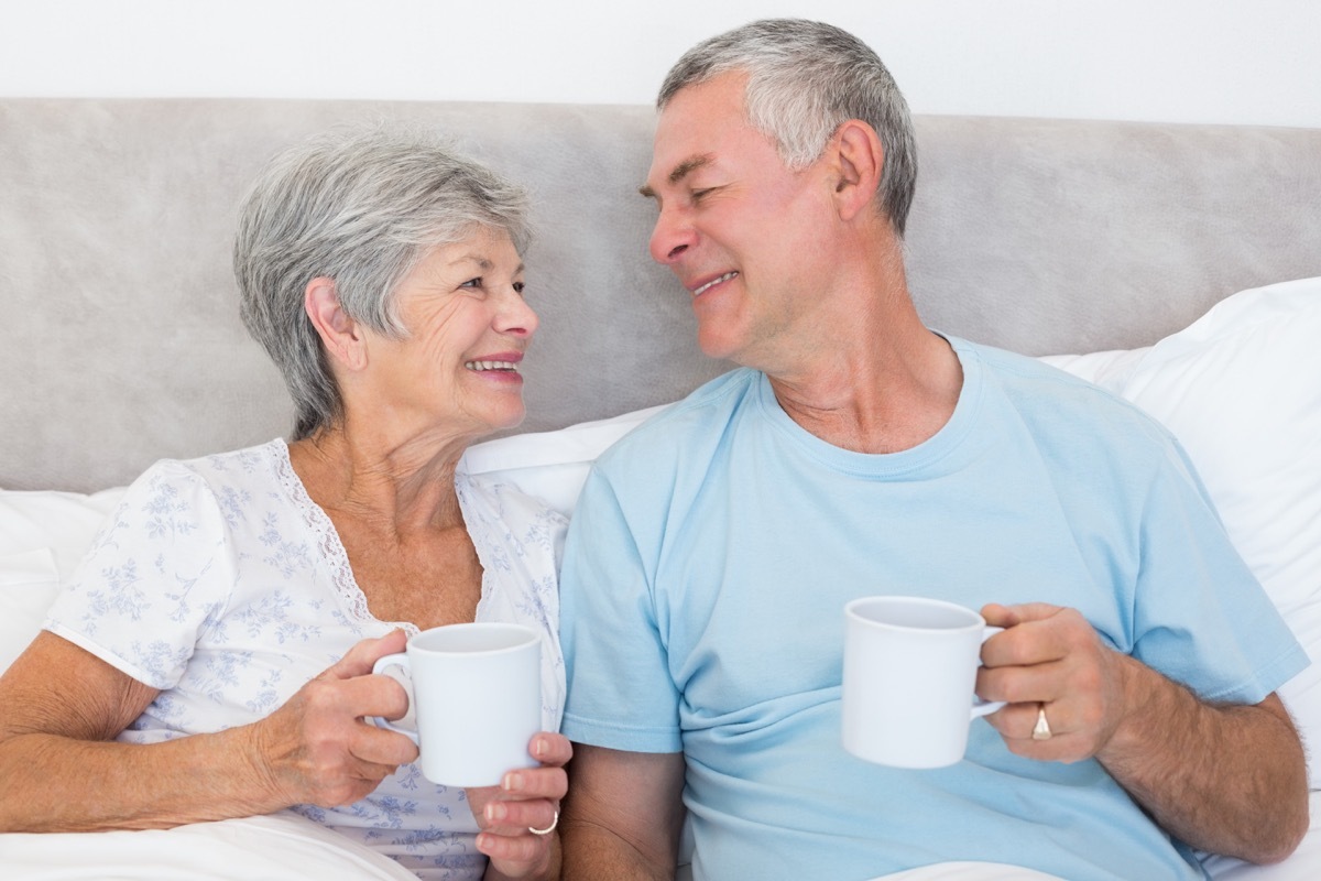 older white straight couple drinking coffee in bed