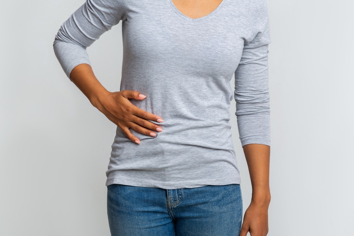 Cropped of girl holding her side, suffering from acute liver pain, grey background