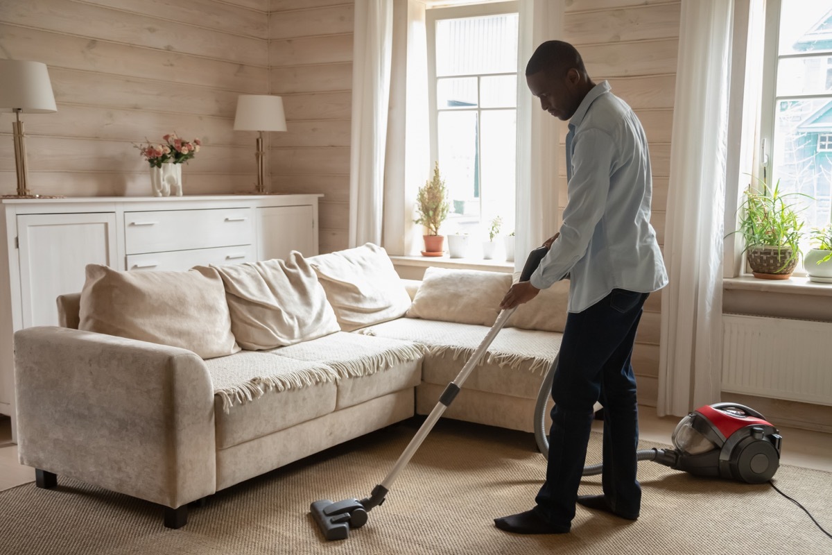 young black man vacuuming carpet