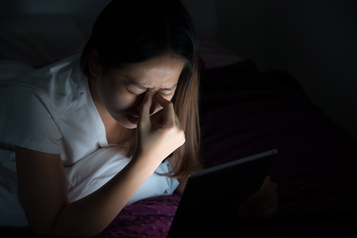 Woman rubbing her eyes in bed at night