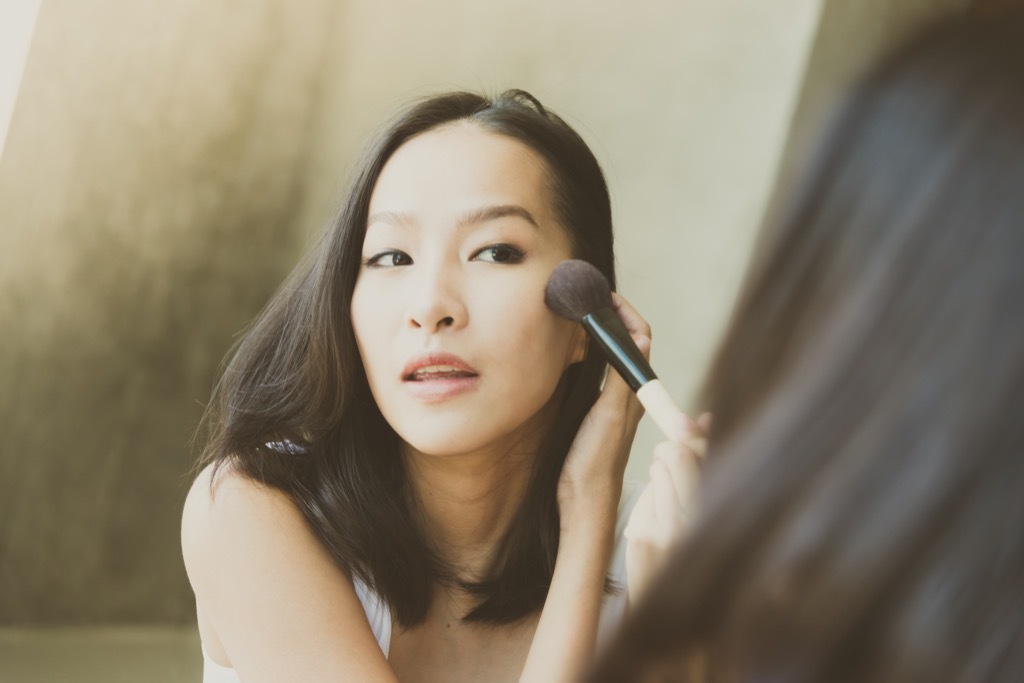 woman applying makeup in mirror, makeup for older women