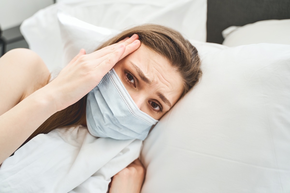 Sad young blonde Caucasian woman in a disposable face mask looking in front of her