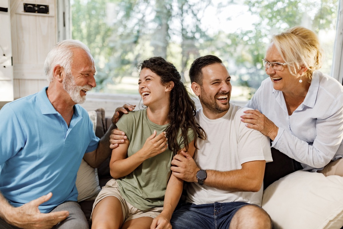 Cheerful couple having fun while talking to senior couple at home.