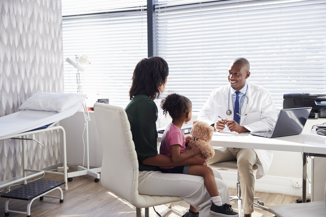 Mother and daughter in office speaking to doctor.