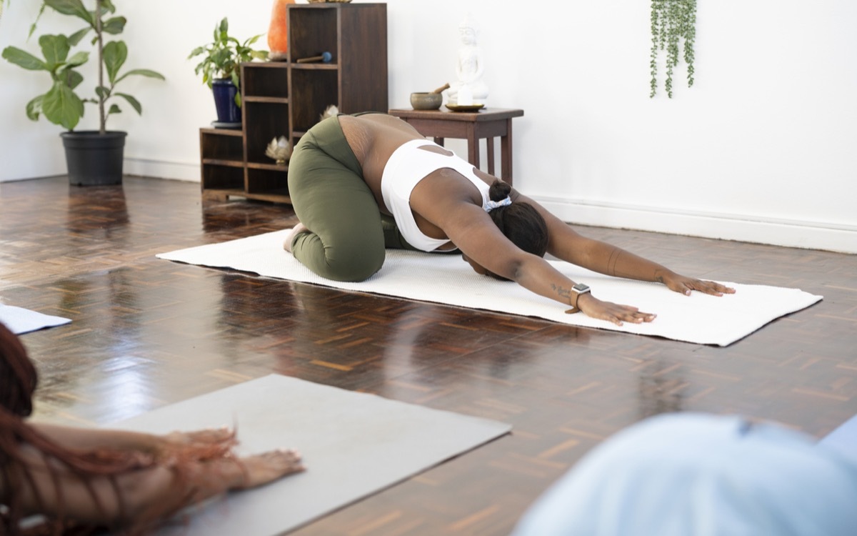 Yoga teacher in childs pose in front of class