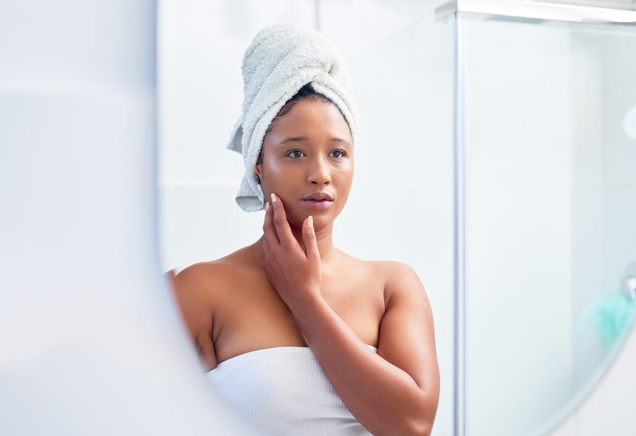 Woman wrapped in towels and looking in the mirror.