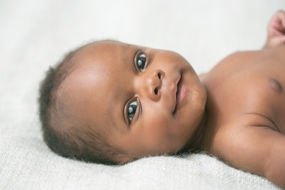 black baby lying down on white bedding