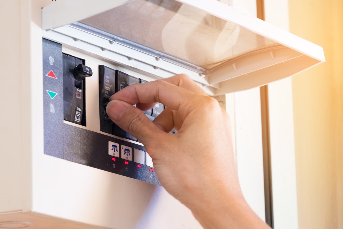 white hand flipping switch in circuit breaker