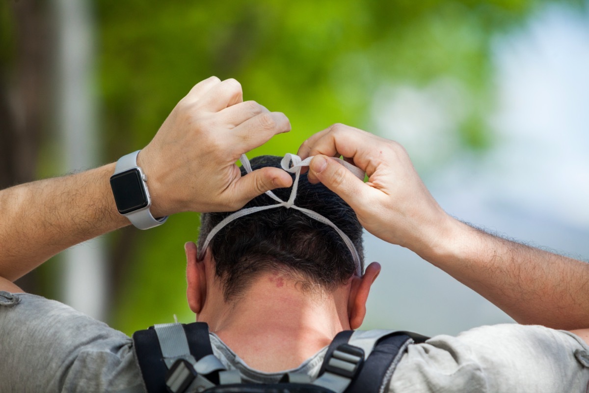 man tying on face mask