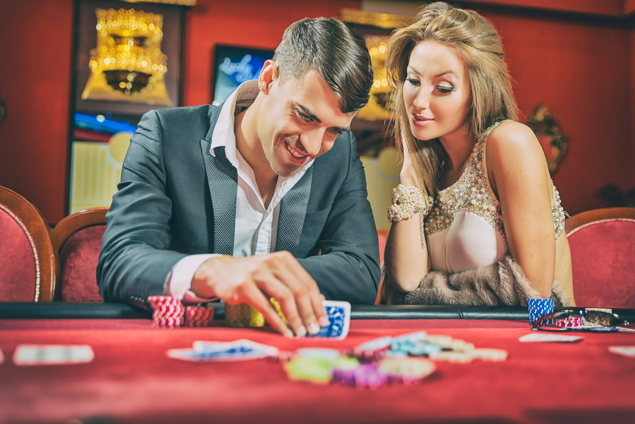 A man playing poker alongside his partner in a casino