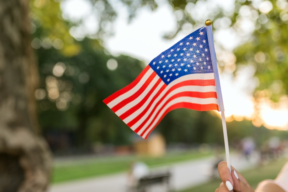 american flag held by white hand