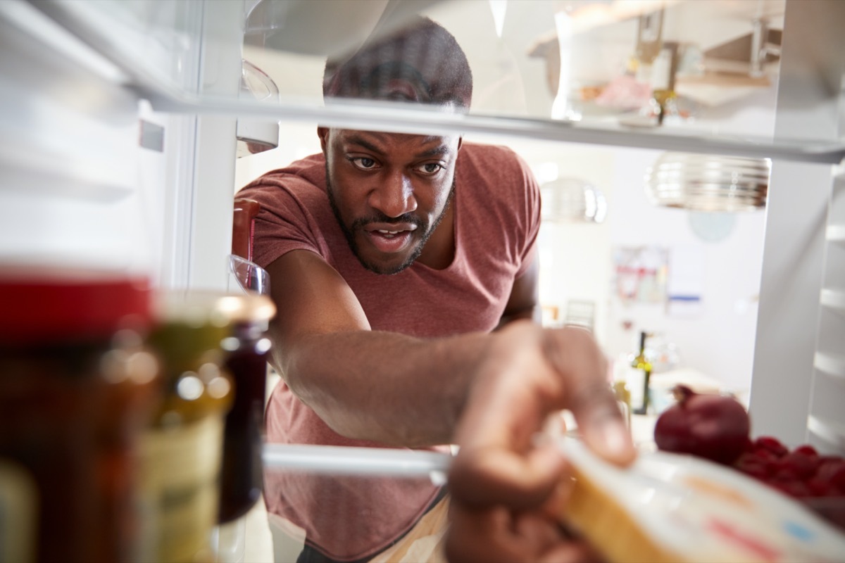 young man reaches into fridge to grab a package