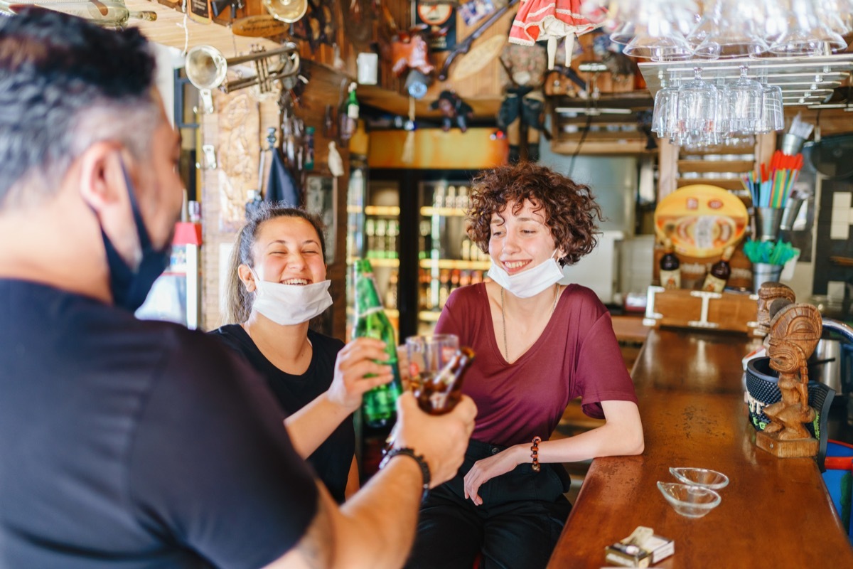 people cheering with beer in bar with illness prevention protection measures are taken