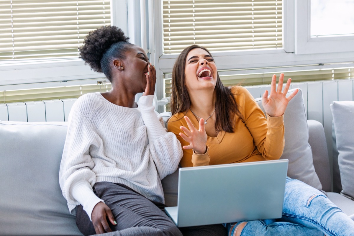 two young female friends watching movie and laughing