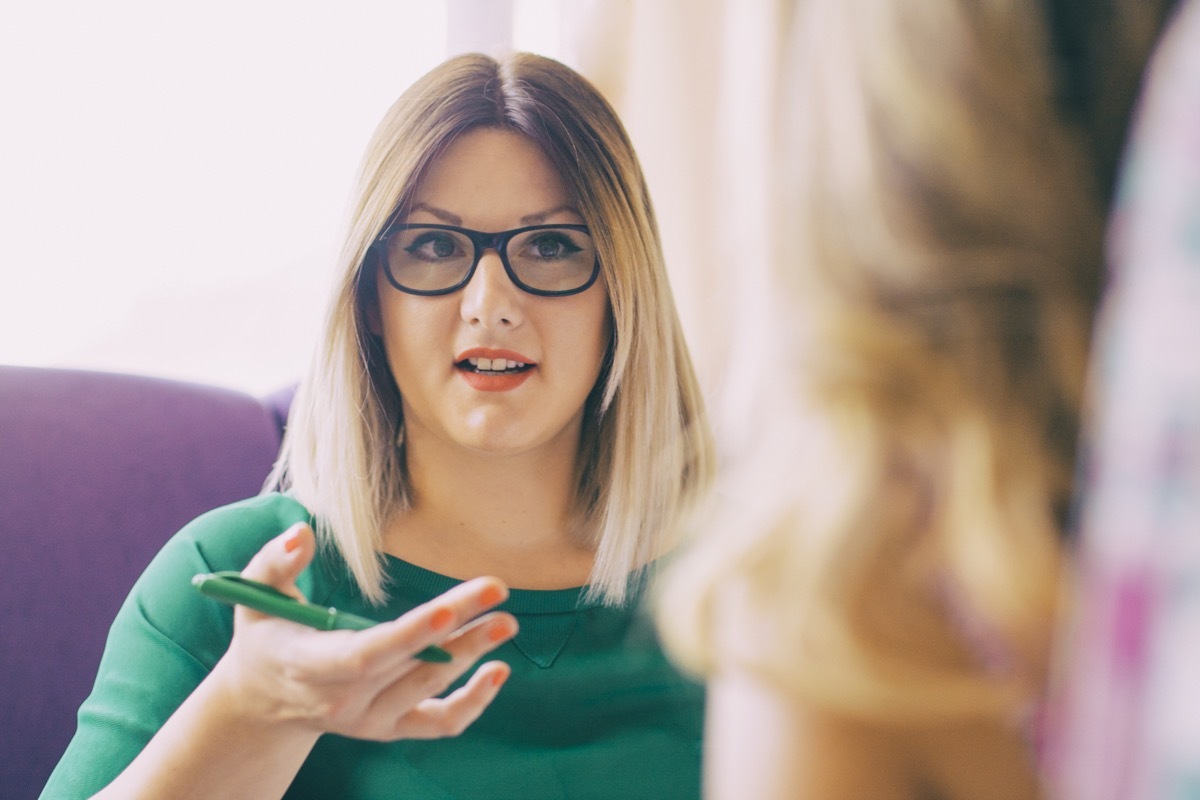 Portrait of young woman talking to an unrecognized person who sits across her