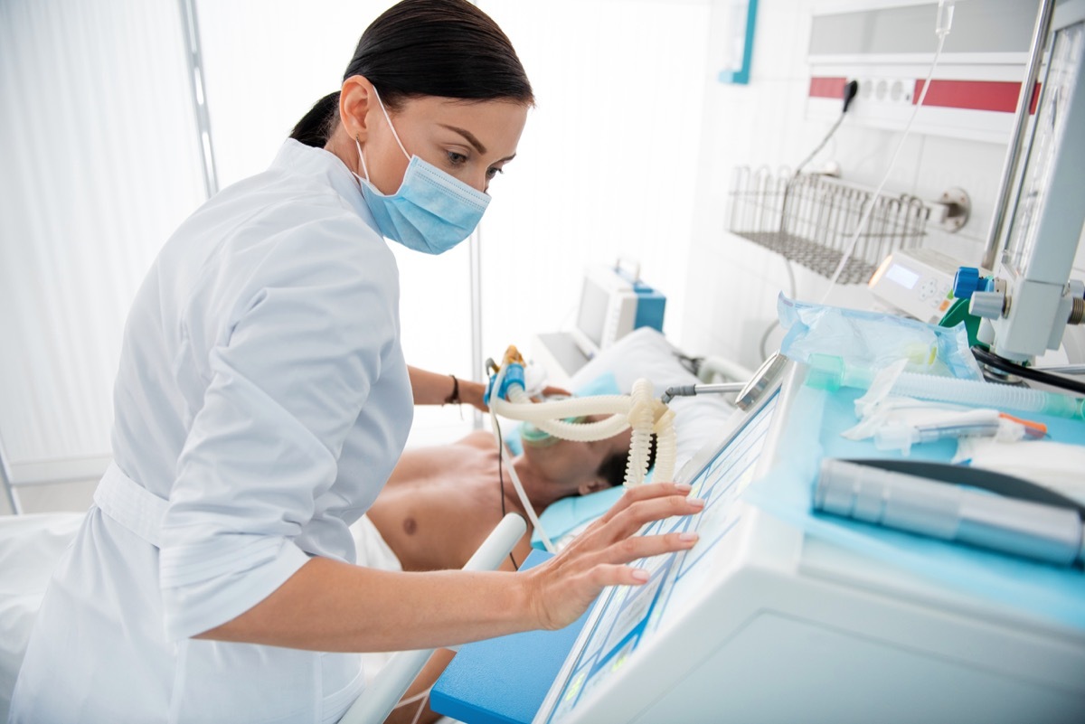 Woman using a ventilator on male patient in hospital