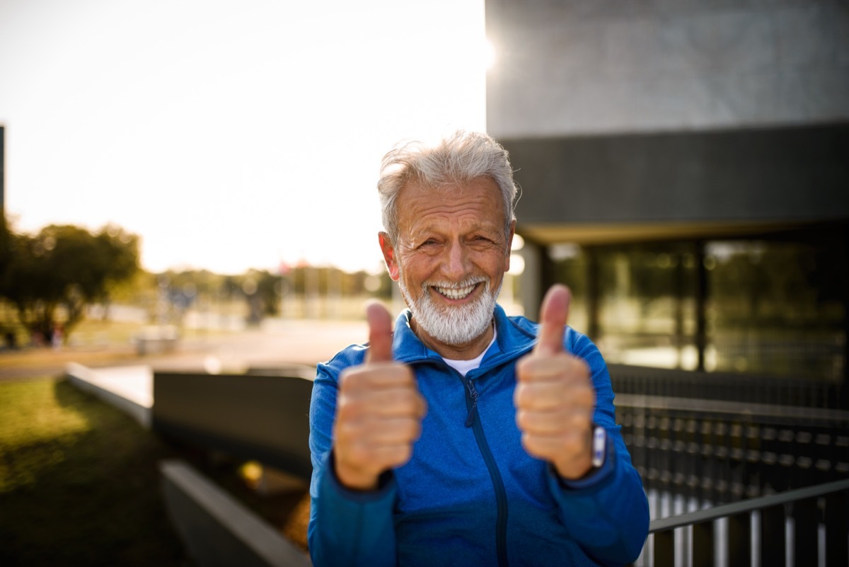 portrait of a smiling senior man showing his thumbs up