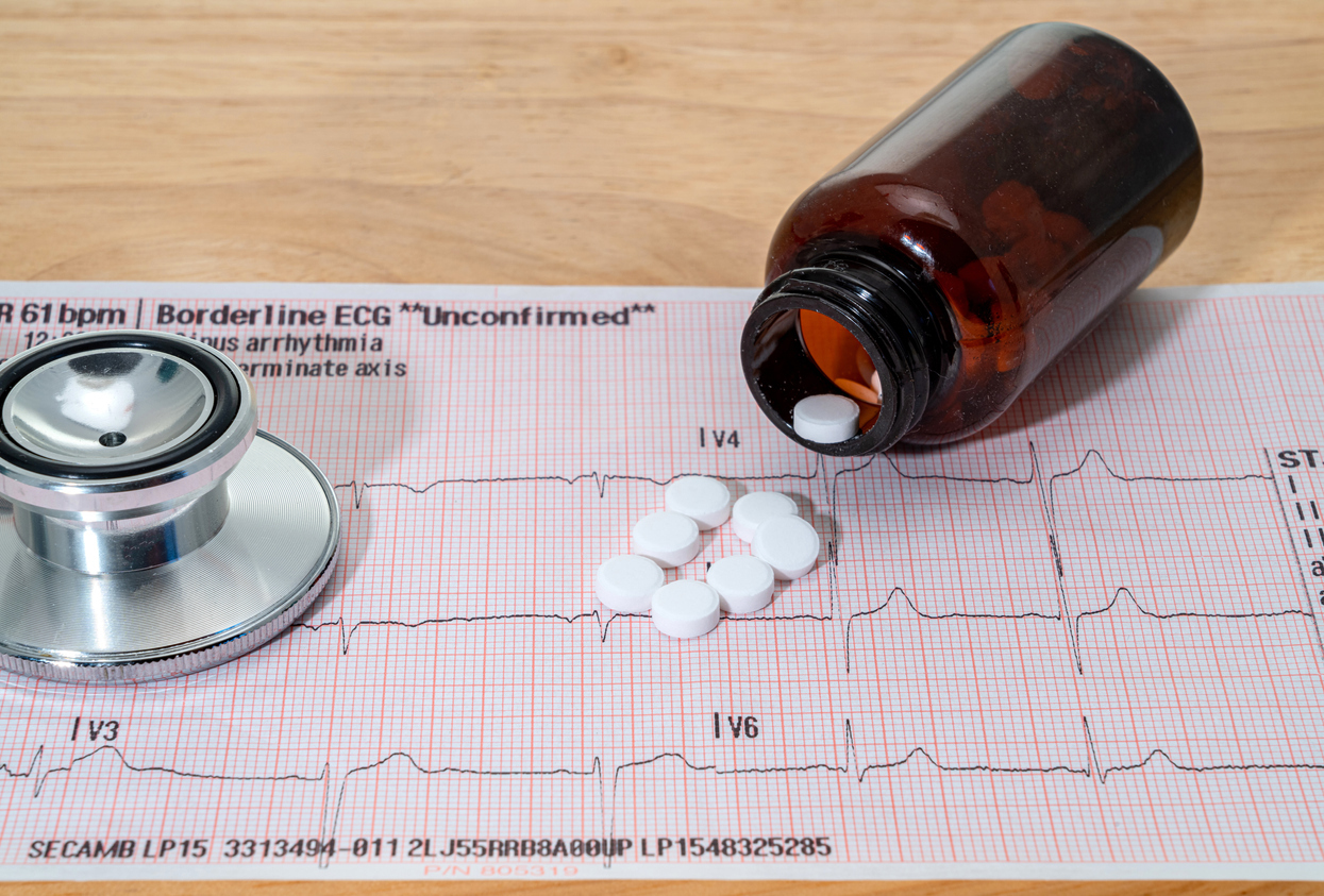 ECG test chart with pills spilling out of a bottle. 