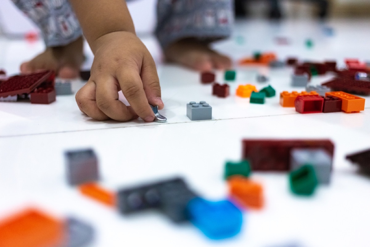 child's hand picking up small toys off the floor, skills parents should teach kids