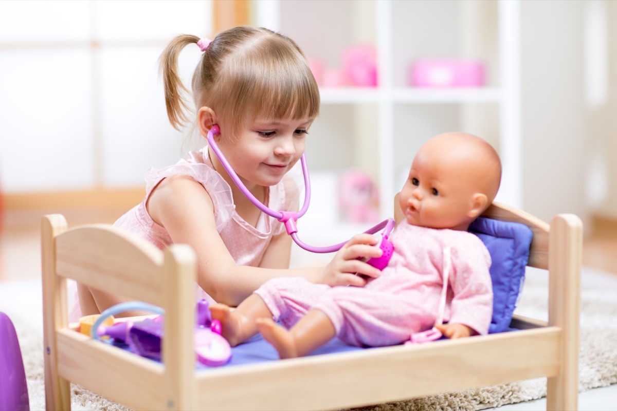 kid girl playing a doctor with doll in kindergarten - Image