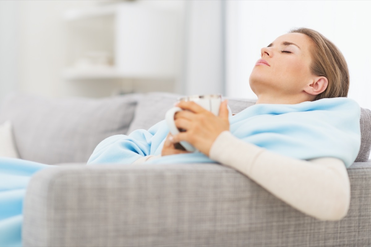 pills pack in hand of ill young woman laying on sofa.