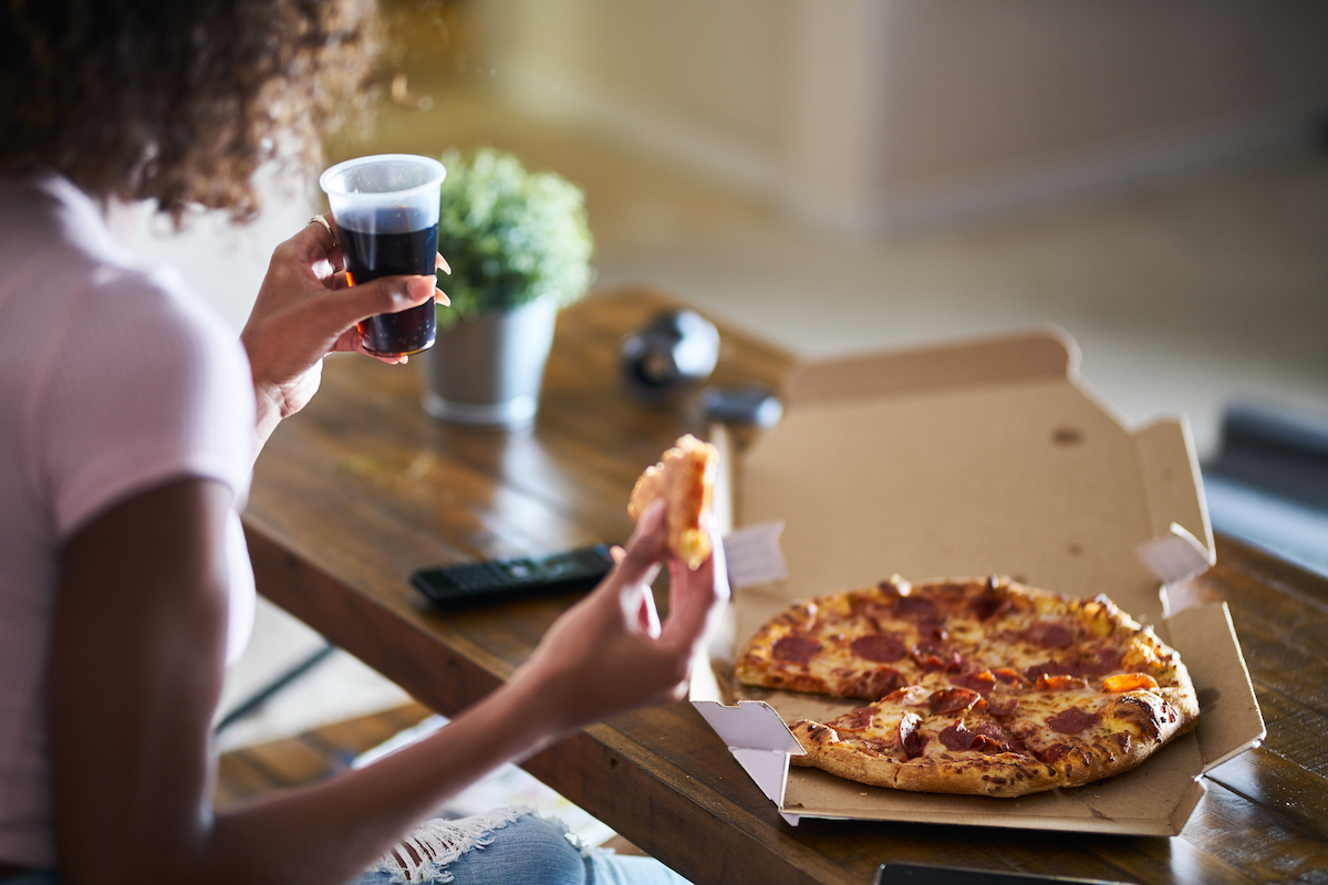 Qoman eating pizza and watching TV