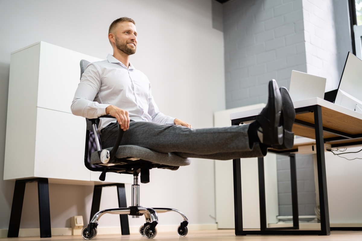 Yoga Workout In Office Behind Business Computer. Gymnastics And Leg Training