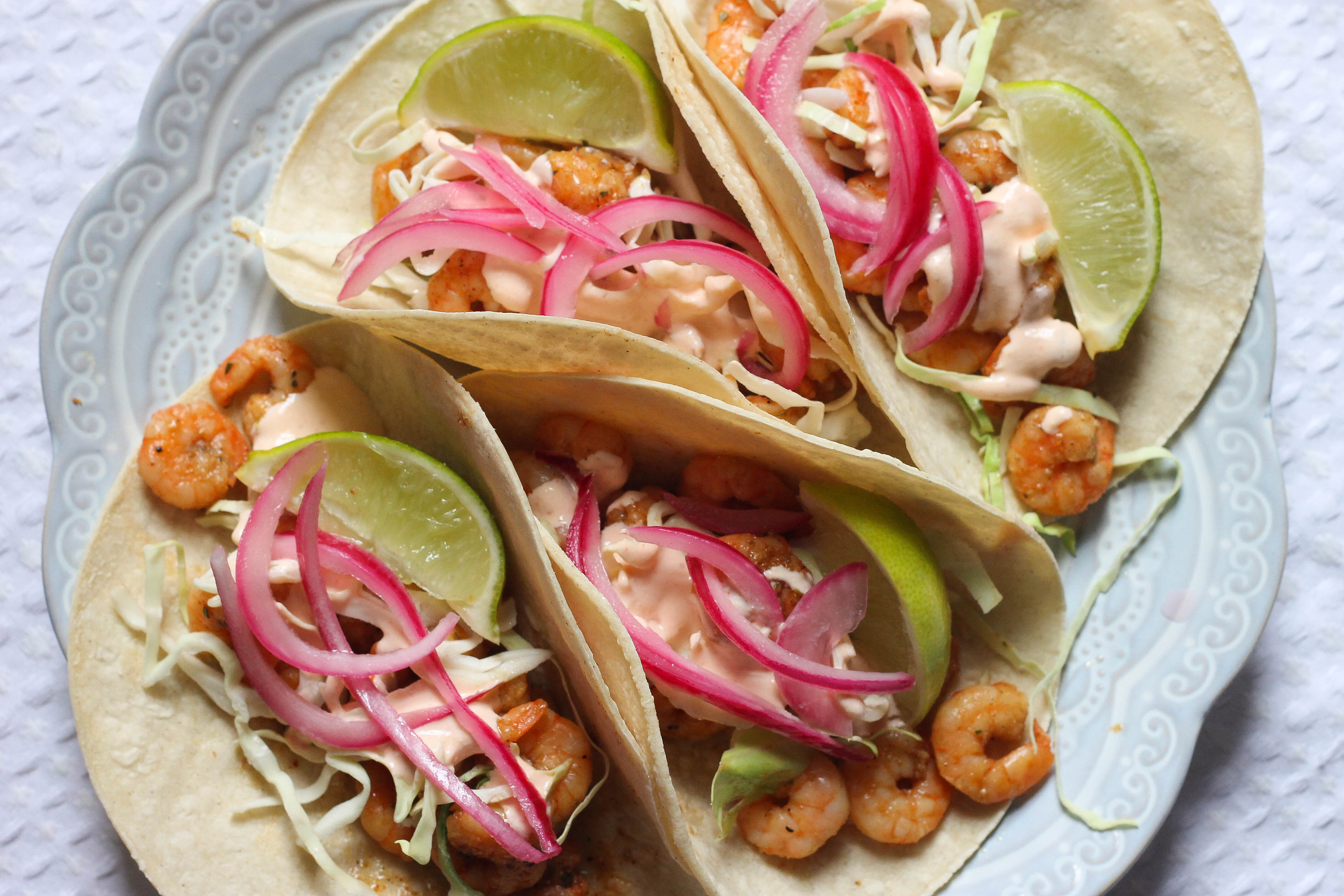 four shrimp tacos on a blue plate