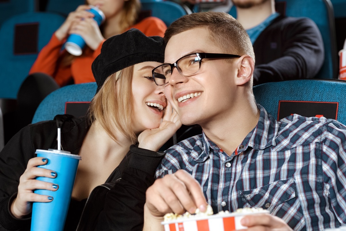 Couple whispering in a movie theater