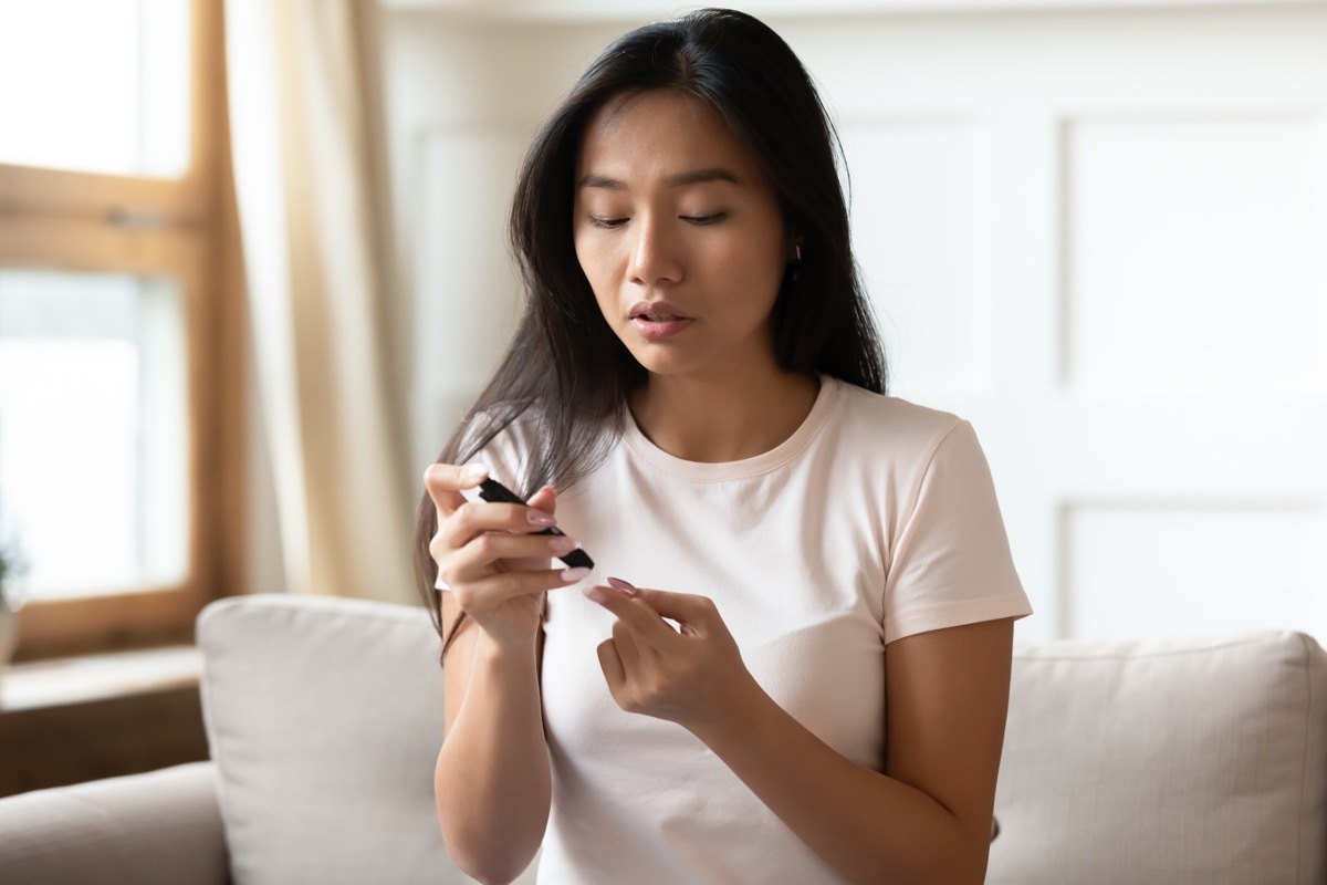 diabetes patient woman sit on couch pinch finger measure blood sugar level at home