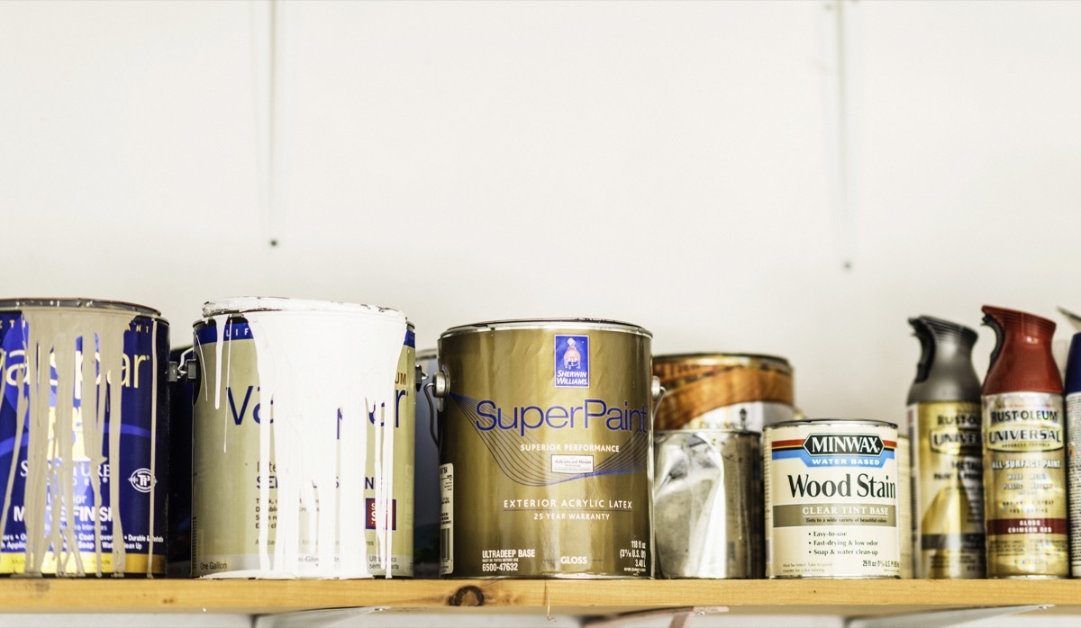 Suffolk, Virginia, USA - June 15, 2014: A horizontal shot of a collection of opened and unopened American brand cans of paint, wood stain and paint sprays organized neatly on a wooden shelf. The brands include cans of indoor house paint by Sherwin Williams and Valspar, spray paint by Rustoleum, and wood stain by Minwax.