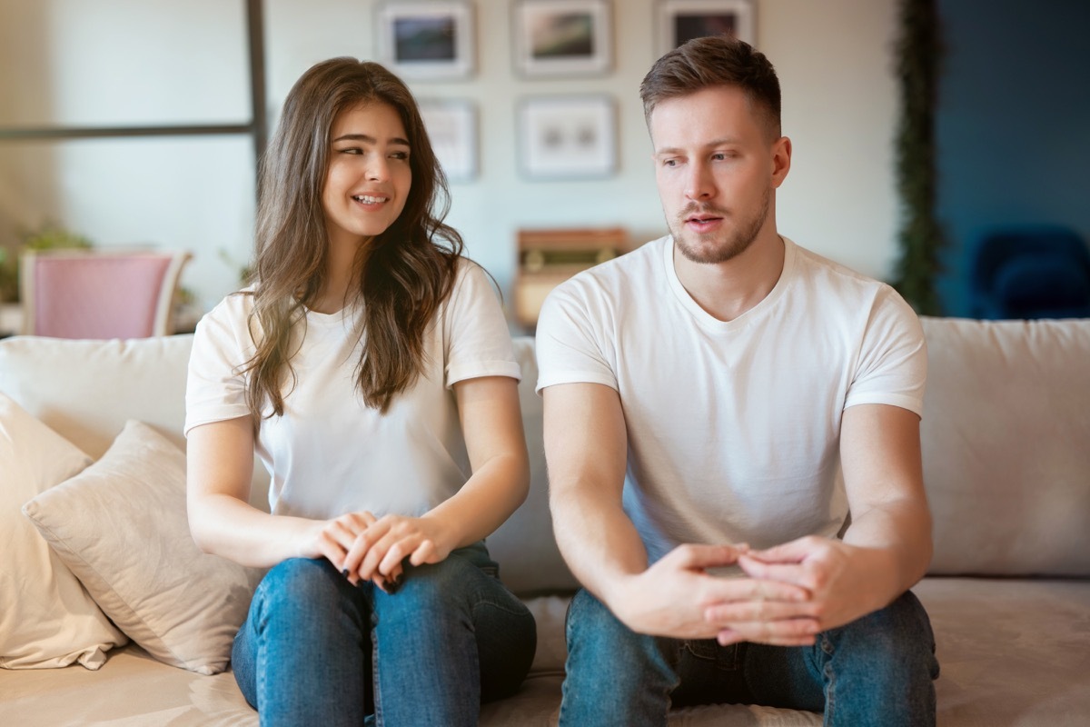 Awkward couple sitting on couch avoiding intimacy