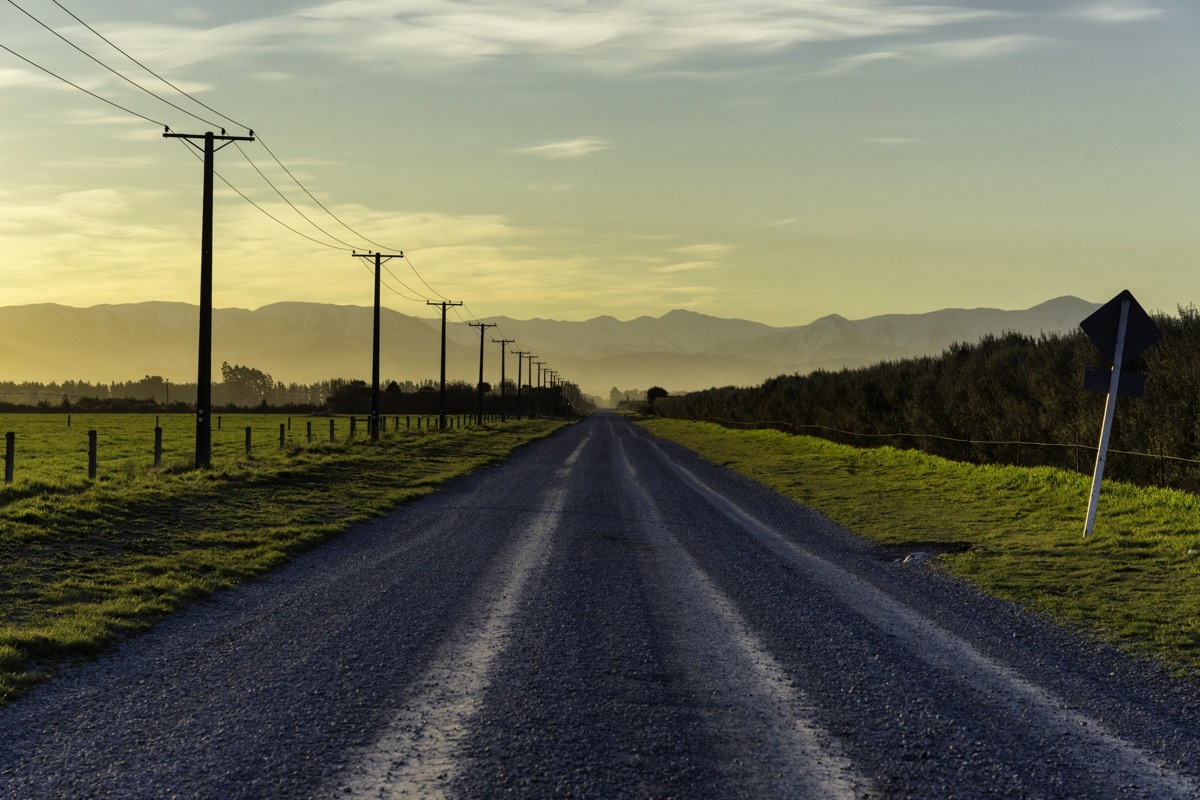 sunset draws closer on a road running towards the Southern Alps, on New Zealand's South Island.