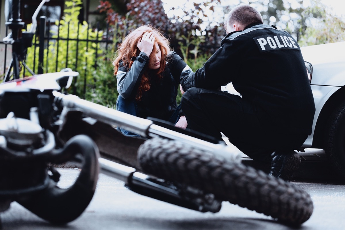 policeman interviewing a dazed driver of a motorbike after a crash