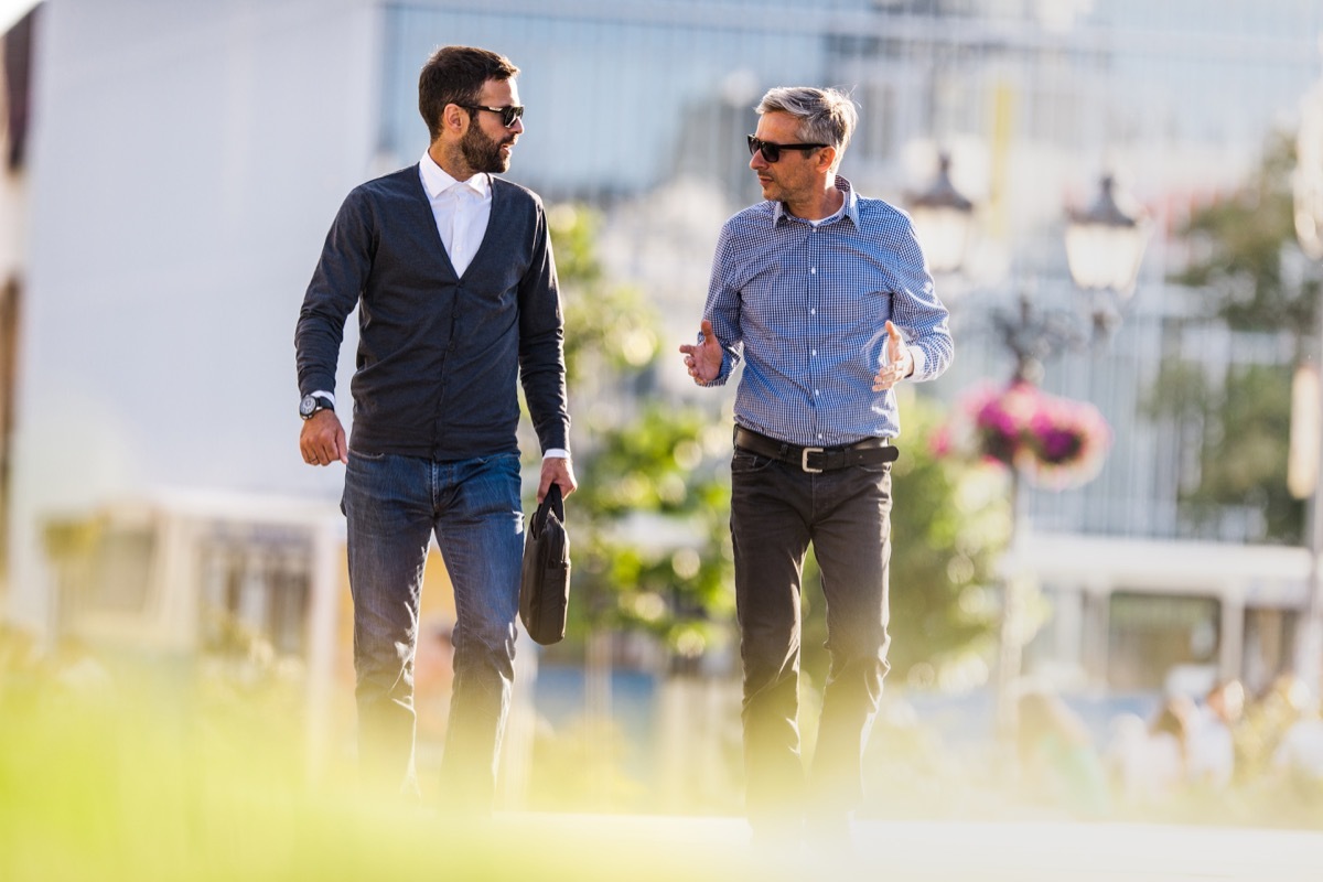 Mid adult business colleagues taking a walk through the city and communicating.